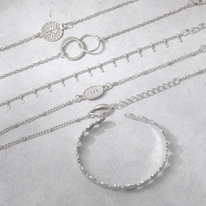 Detailed set of silver bohemian bracelets featuring pineapple, shell and coin pendants