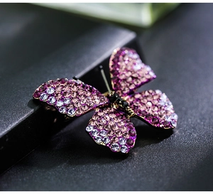 Macro shot of purple gradient crystal butterfly brooch with pavé rhinestones in dark setting