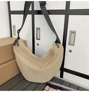 Detail of beige nylon crossbody bag with adjustable black strap and side zipper pocket