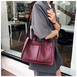 Detail of burgundy leather tote bag with dual front pockets and shoulder strap for women