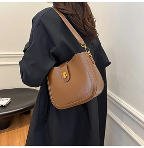 Detail view of a vintage brown saddle bag with shiny patent texture and gold buckle