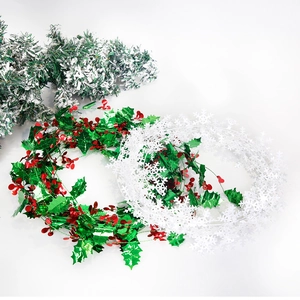 Christmas garland set with green holly leaves, red berries and white snowflake tinsel