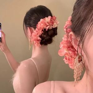 Close-up of pink fabric flower hairpin and golden tassel earrings on model hair