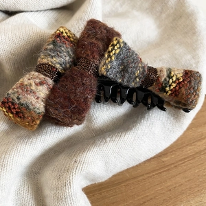 Detailed view of the winter bow hair claw with multi-colored tweed fabric texture