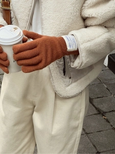 Primer plano de guantes de punto de lana color caramelo con función táctil y etiqueta tejida