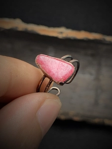 Close-up of pink irregular raw stone ring with double-loop hollow dark metal band