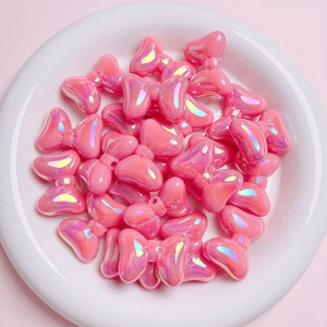 Close-up of pink iridescent bow-shaped acrylic beads arranged in a white decorative tray
