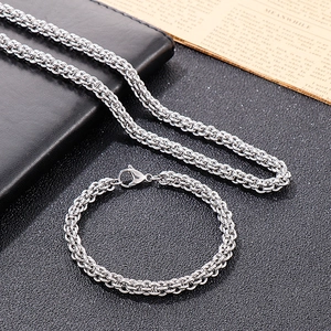 Polished silver Byzantine chain necklace and bracelet set for men on black textured background