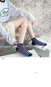 Detail of blue and white striped cotton ankle socks worn by a model in casual setting