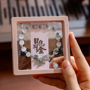 Blue beaded butterfly bracelet in a pink floating jewelry display frame with gift card