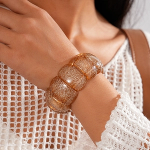 Detail of amber glitter acrylic modular bracelet worn with boho style white mesh top