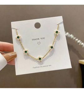 Detail of vintage emerald flower bracelet with gold chain and small pearl accents
