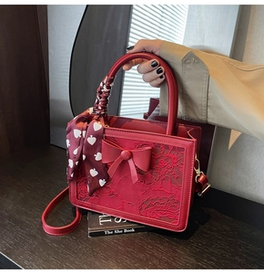 Detail of red bridal handbag with floral lace texture, bow decoration and silk scarf handle