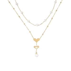 Détail d'un collier double rang doré avec perles blanches et pendentifs coeur sur fond blanc