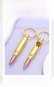 Detail of bullet-shaped keychain with bottle opener in polished gold and copper finish