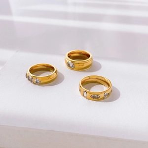Three-piece gold plated ring set featuring various zircon shapes on a minimalist stand