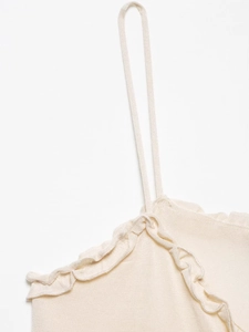 Detail of ruffle edge and fine knit texture on a cream sleeveless camisole top