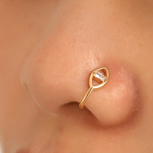 Macro detail of a non-pierced gold U-shaped nose cuff with marquise frame and zircon stone