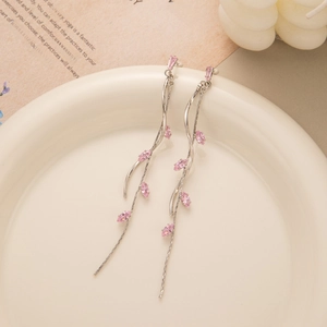 Detail of elegant leaf tassel earrings with pink zircons on a white ceramic plate