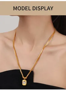 Close-up of a double-layered gold snake chain necklace with a heart-shaped crystal pendant