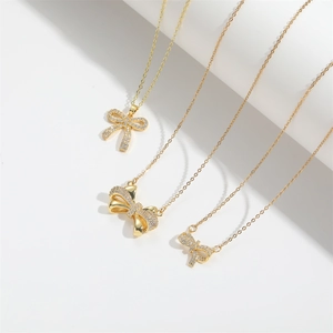 Three gold bow pendant necklaces with pavé zircon stones on a clean white background