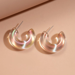 Close-up of geometric C-shaped acrylic earrings with iridescent polar light effect