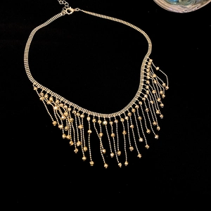 Close-up of golden tassel necklace with delicate metal mesh and beaded fringe details