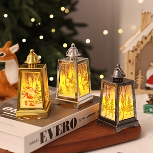 Three trapezoidal Christmas lanterns with LED lights and holiday prints on a wood tray