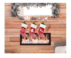 Three Christmas stockings with snowflake and reindeer patterns hanging over a cozy fireplace