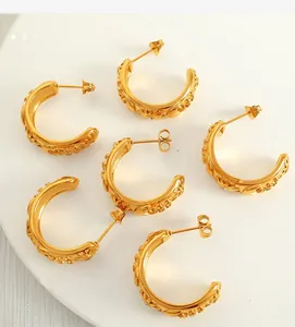 Macro detail of six gold C-shaped hoop earrings with vintage floral relief patterns