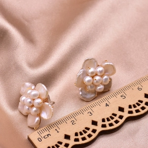 Elegant natural pearl flower earrings with gold metal base on champagne silk fabric