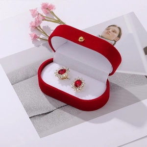 Detail of vintage red gemstone earrings with rhinestones next to a red velvet jewelry box