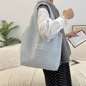 Shoulder view of light blue textured knit tote bag with brand label and large capacity