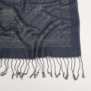 Dettaglio del motivo paisley jacquard su una sciarpa blu navy e grigia con frange