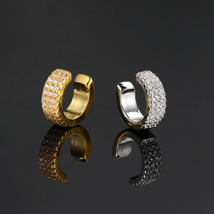 Detail of gold and silver C-shaped ear cuffs with sparkling zircon rows on black background