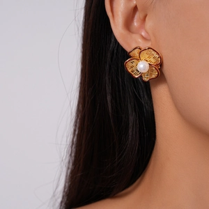 Detail of 18k gold plated hollow flower earring with woven texture and central pearl