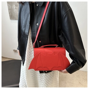 Detail of red bat-wing shaped leather handbag styled with gothic fashion accessories