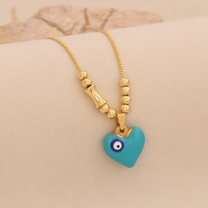 Détail du collier chaîne à billes dorées avec cœur en émail bleu et pendentif mauvais œil