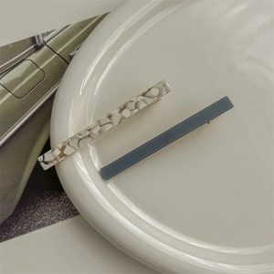 Close-up of elegant acetate hair clips in blue and gold flakes on a ceramic tray