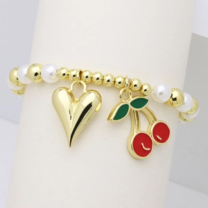 Close-up of beaded bracelet with gold beads, pearls, heart charm, and cherry pendant detail