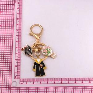 Close-up of golden graduation keychain with enamel cap, gown, and bouquet charms