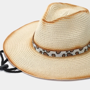 Close-up of beige straw hat featuring leopard pattern rhinestone trim and black wind cord