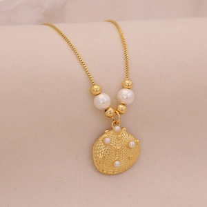Detail of gold shell pendant with pearls on a delicate beach style necklace