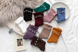 Detail of ribbed knit socks with elegant pearl accents and delicate ruffled edge cuffs
