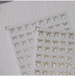 Macro view of 3D embossed bow nail stickers in gold and silver metallic finishes