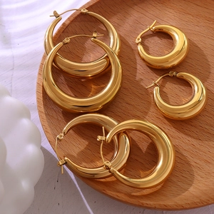 Tre paia di orecchini a cerchio a U placcati in oro 18K su un vassoio di legno lucido