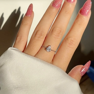 Détail d'une bague avec pierre en poire et anneau ajustable en chaîne sur la main