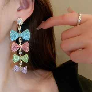 Elegant gold bow tassel earrings with colorful gradient rhinestones on fashion model