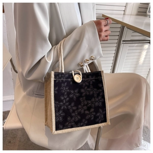 Detailed macro view of black floral canvas lunch bag with rustic wooden button and rope handle