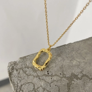 Macro shot of irregular wavy textured rectangular pendant on a fine 18K gold chain